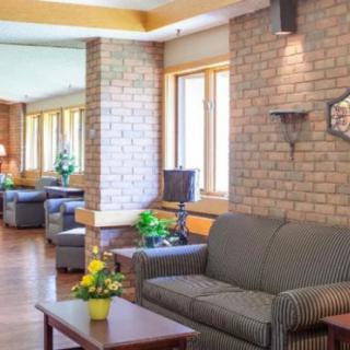 A cozy living room with brick walls, featuring a comfortable sofa, coffee table, and windows letting in natural light.