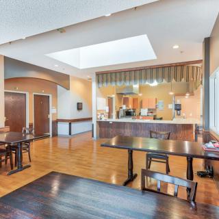 A modern open-space kitchen and dining area with wooden floors and contemporary furniture.