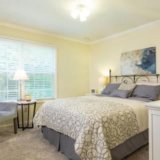 A cozy bedroom with a neatly made bed, bedside lamps, and tasteful decorations.