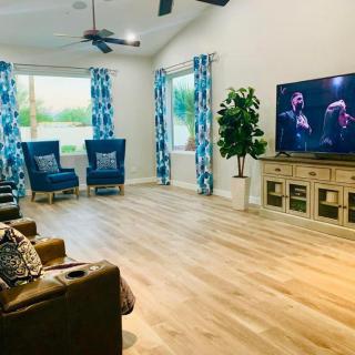 A spacious living room with modern decor, featuring a television, blue seating, and vibrant curtains.