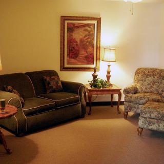 A cozy living room with a sofa, armchair, and warm lighting.