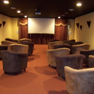 A cozy cinema room with arranged seating facing a large screen.