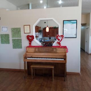 A cozy interior featuring a decorative piano surrounded by hearts and artwork.