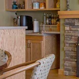 A cozy kitchen bar area with wooden cabinets and a stone fireplace.