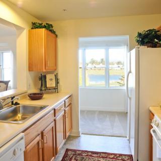 A bright kitchen with wooden cabinets and a large window overlooking a scenic view.