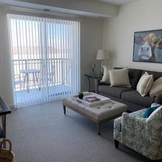 A cozy living room featuring a gray sofa, a stylish coffee table, and abundant natural light streaming through vertical blinds.