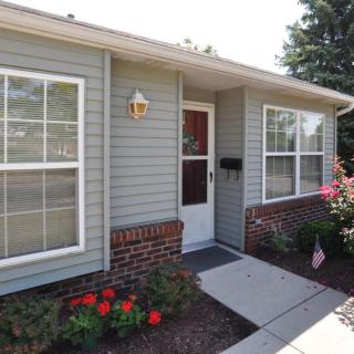 A cozy residential house with a front entrance, landscaped garden, and sidewalk.