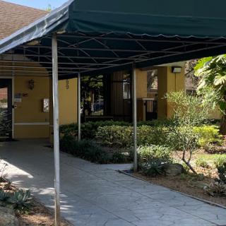 A covered walkway leading to an entrance, surrounded by well-maintained greenery.