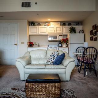 A cozy living room with a white sofa and a view of the kitchenette.
