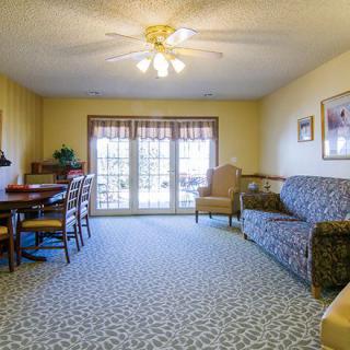 A cozy living room with a sofa, dining area, and large windows.
