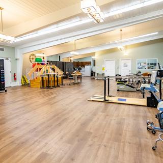 A spacious fitness studio with various exercise equipment and a wooden floor.