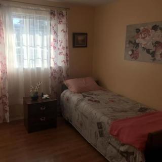 A cozy bedroom with a single bed, floral curtains, and a nightstand by the window.