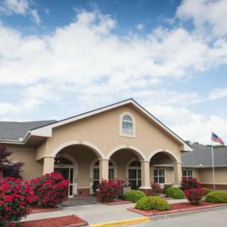 A charming building with arched entrances, surrounded by lush landscaping and under a partly cloudy sky.