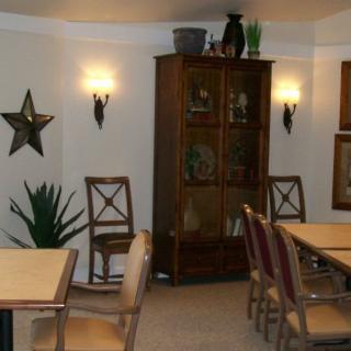 A cozy dining room with wooden tables and chairs, a cabinet, and decorative elements on the walls.