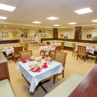 A well-furnished dining area with neatly arranged tables and chairs, featuring warm lighting and tasteful decor.
