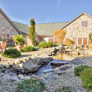 A picturesque stone house with a beautifully landscaped garden and a small pond.