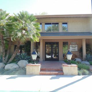 Front view of a residential house with palm trees and landscaped entrance.