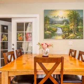 A cozy dining room with a wooden table, chairs, and a landscape painting on the wall.