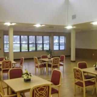 A spacious dining room with neatly arranged tables and chairs, large windows providing natural light.