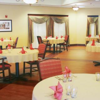 A well-arranged dining room with round tables, red napkins, and stylish decor.