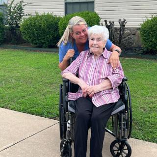 A joyful moment shared between a caregiver and an elderly person enjoying time outdoors.