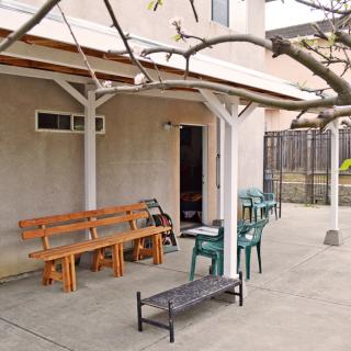 A backyard patio with a variety of outdoor seating options under a pergola.
