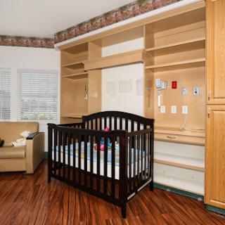 A cozy nursery featuring a dark wooden crib, modern shelving, and comfortable seating.