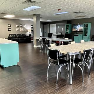 A modern office space with an open layout, featuring tables and chairs, a sofa, and a television.