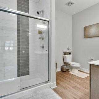 A modern and minimalist bathroom with a glass shower and wooden floor.