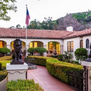 A charming house with a well-manicured garden, featuring a prominent statue and an American flag.