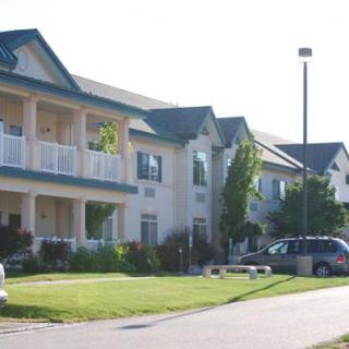 A suburban residential building with apartments and a nearby parking lot.