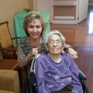 A joyful moment shared between a caregiver and an elderly woman in a wheelchair.