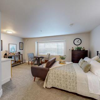 A cozy and well-decorated bedroom featuring a comfortable bed, a desk area, and ample natural light.
