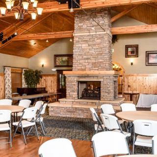 A cozy dining area with a central stone fireplace and wooden ceiling.