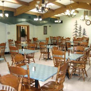 An empty dining area with wooden tables and chairs in a restaurant setting.