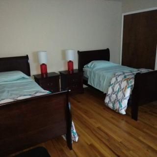 A cozy bedroom featuring twin beds with matching lamps on a nightstand and a hardwood floor.