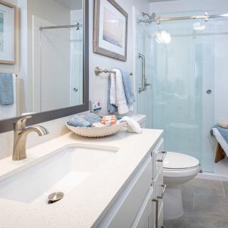 A modern, well-lit bathroom with a sleek design featuring a large mirror, countertop sink, and glass shower enclosure.