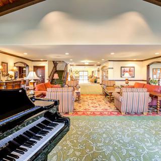 A spacious living room featuring a grand piano, elegant furniture, and stylish decor.