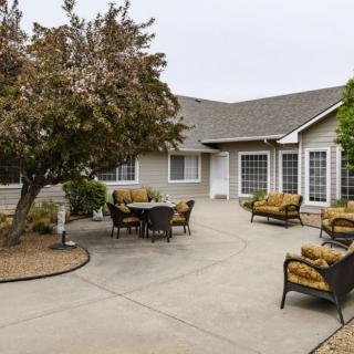 A spacious patio with comfortable outdoor furniture and a tree, adjacent to a house.