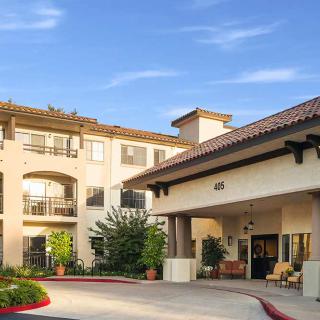 Exterior view of a residential building with an entrance and landscaped surroundings.