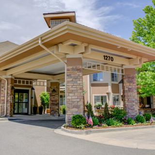Exterior view of a building entrance with an awning and landscaped surroundings.