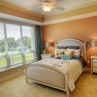A cozy and elegantly decorated bedroom with a large window allowing natural light to illuminate the space.