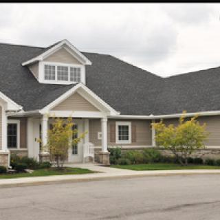 A charming residential building featuring a gabled roof and landscaped surroundings.