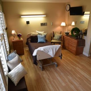 A cozy and inviting massage room with a therapy bed, soft lighting, and wooden floors, designed for relaxation and comfort.