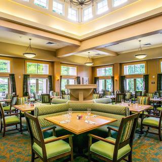 A spacious and well-lit dining area featuring neatly arranged tables and chairs, surrounded by large windows.