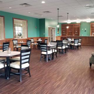 An empty restaurant dining area with neatly arranged tables and chairs on a hardwood floor.
