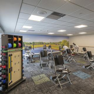 A fitness room equipped with exercise chairs and colorful dumbbells.
