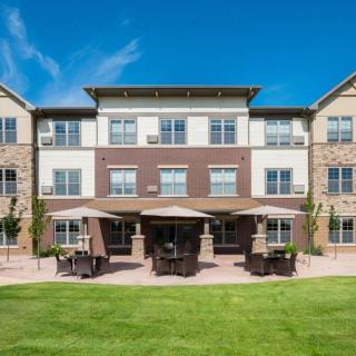 A residential building with a well-maintained lawn and outdoor seating area.