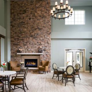 A cozy interior living room with a large brick fireplace, elegant chandelier, and stylish furniture.
