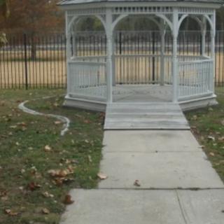 A gazebo with a paved pathway leading to it in a park setting.
